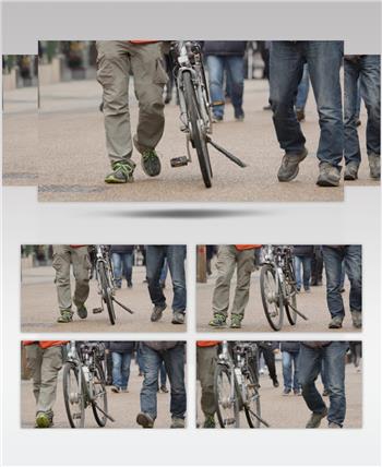 中镜头看在英国牛津繁忙的街道上推着自行车的人们