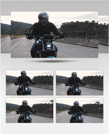 一个穿着黑色皮夹克，蓝色牛仔裤和白色头盔的人骑着摩托车在路上
