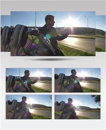 公路旁一个戴太阳镜的男人坐在摩托车上抽烟