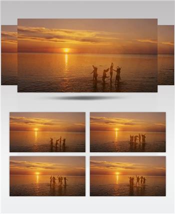 日落夕阳下的海边一群好朋友在海面上跳跃