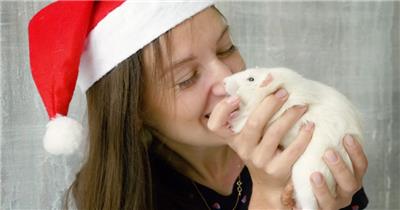 女生戴着圣诞帽抱着一只小白鼠
