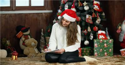 年轻女子在圣诞树上写一封信
