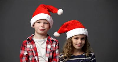 在镜头前两个孩子戴着圣诞帽