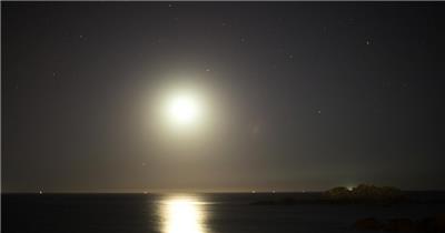延时摄影夜空中月亮和海上的星星
