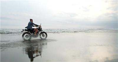 在海边骑摩托车的嬉皮士男子