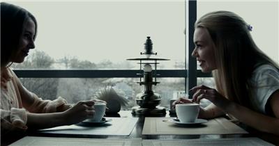 两个女孩在咖啡馆边喝咖啡边聊天