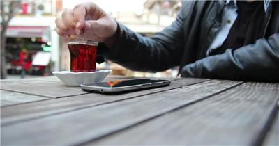 实拍一位边喝茶时边玩手机的男人
